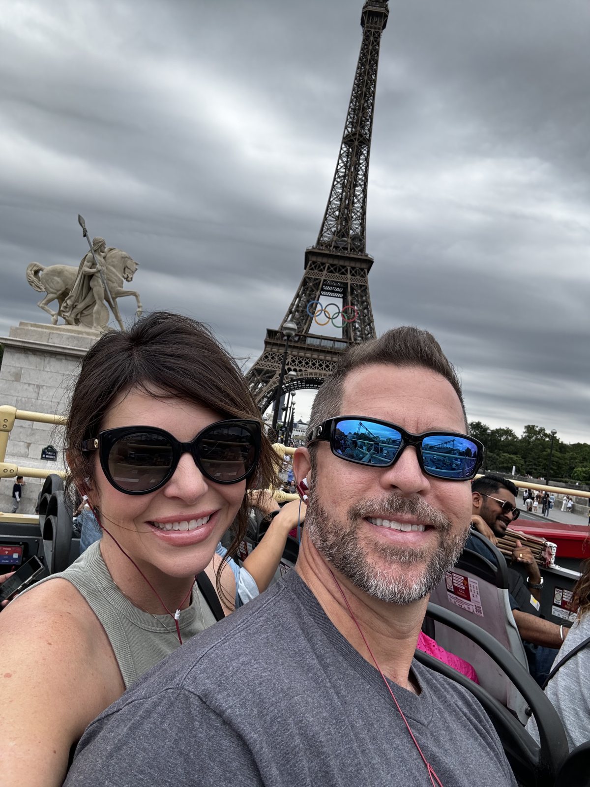 Liane and a companion smiling in front of the Eiffel Tower with the Olympic rings