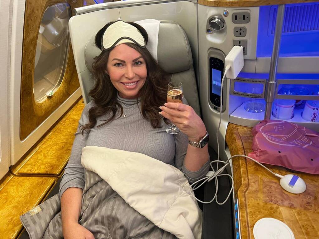 Liane raising a glass of champagne in her Emirates A380 seat